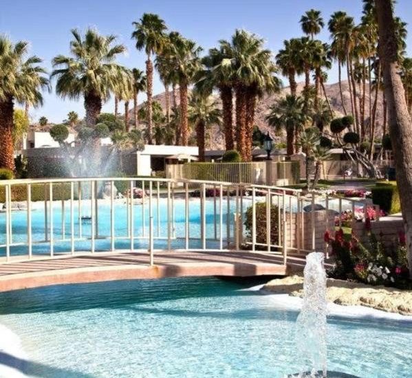 Photo of exterior grounds with swimming pool, palm trees and water fountains