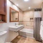 Photo of bathroom with white sink and white bath tub.